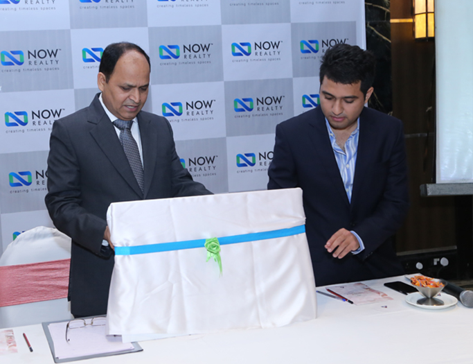 NOW Realty executives are unveiling a covered display during a formal event.