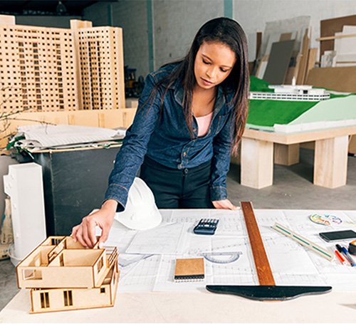 Smiling engineer in a yellow hard hat standing confidently at a construction site.