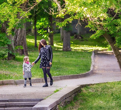 Young woman enjoying fresh air outdoors while holding a bunch of yellow flowers.