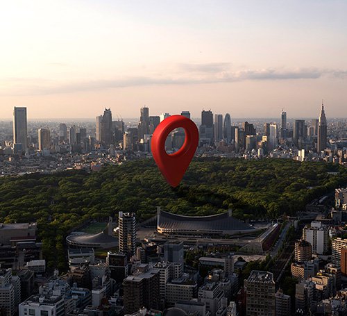 Hands using a tablet to locate a NOW Realty property on a digital map, with a modern residential building in the background
